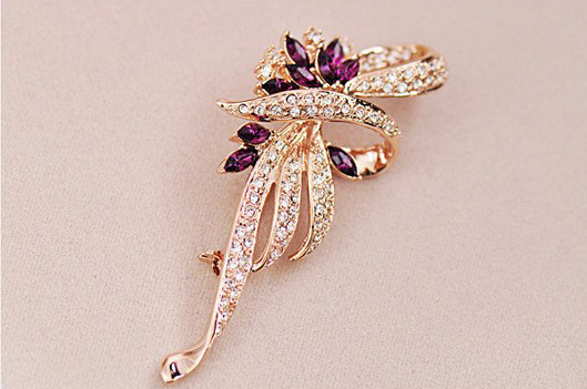 Luxusná brošňa v tvare ornamentu v zlatej farbe s fialovými kryštálmi