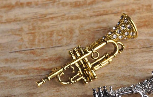 Zlatá brošňa na oblečenie v tvare prepracovaného saxofónu