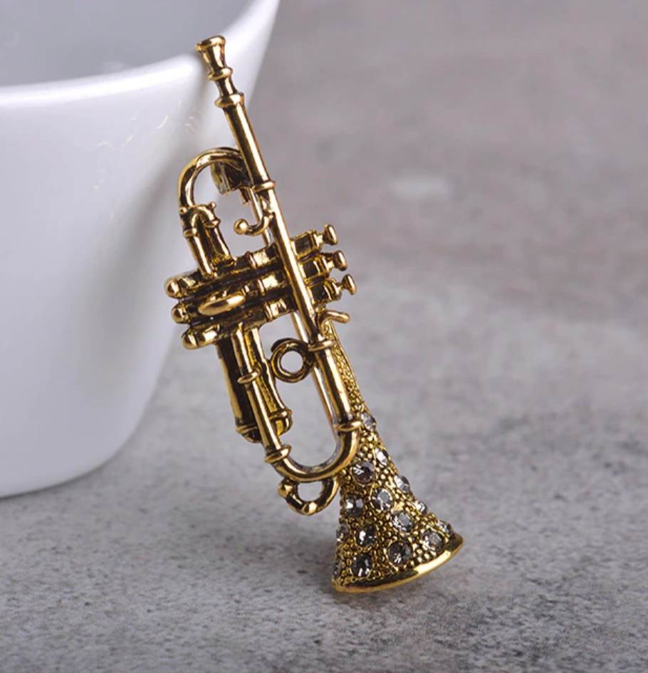 Zlatá brošňa na oblečenie v tvare prepracovaného saxofónu